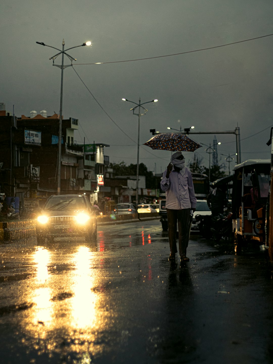 a-woman-walking-down-a-street-holding-an-umbrella-zvjqrzmmir8