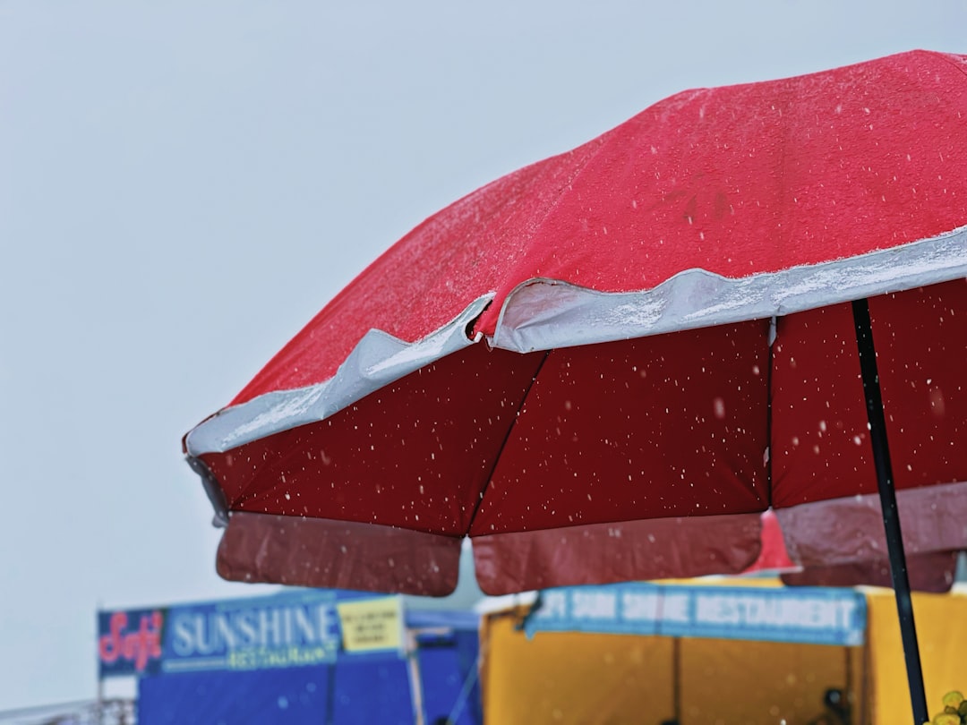 a-red-umbrella-sitting-on-top-of-a-sandy-beach-nsjqsioqnoy