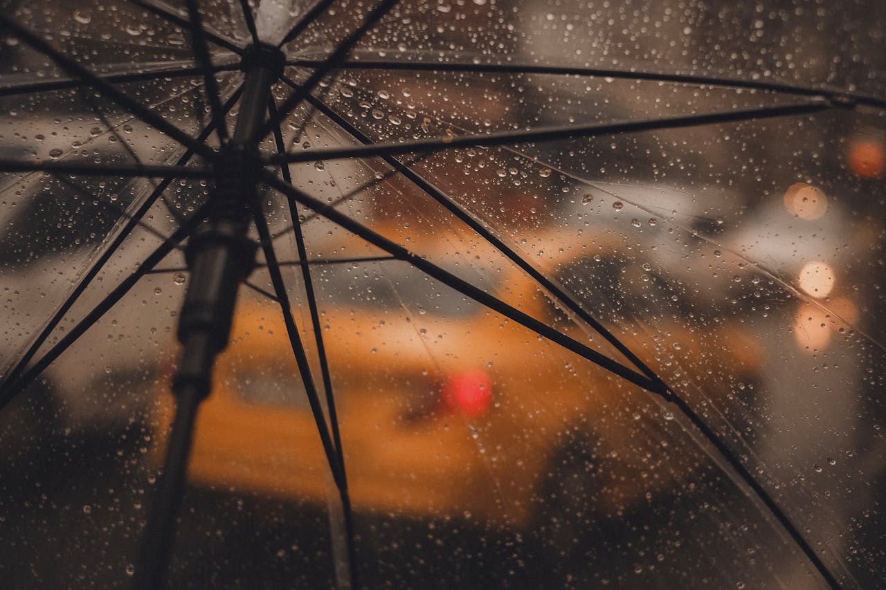 Rainy day scene in Istanbul with water droplets on an umbrella and a blurred taxi background.